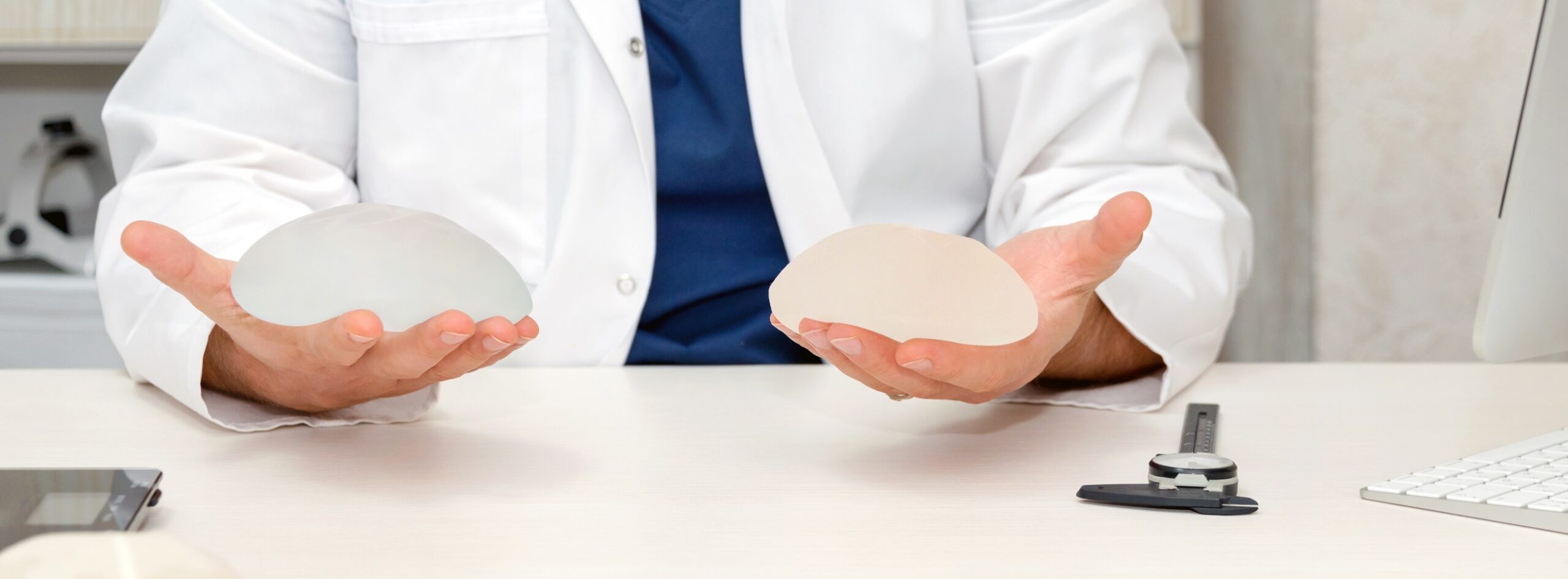 Doctor holding silicone implants for breast augmentation, space for text. Plastic surgeon hands holding silicon breast implants. Cosmetic surgery